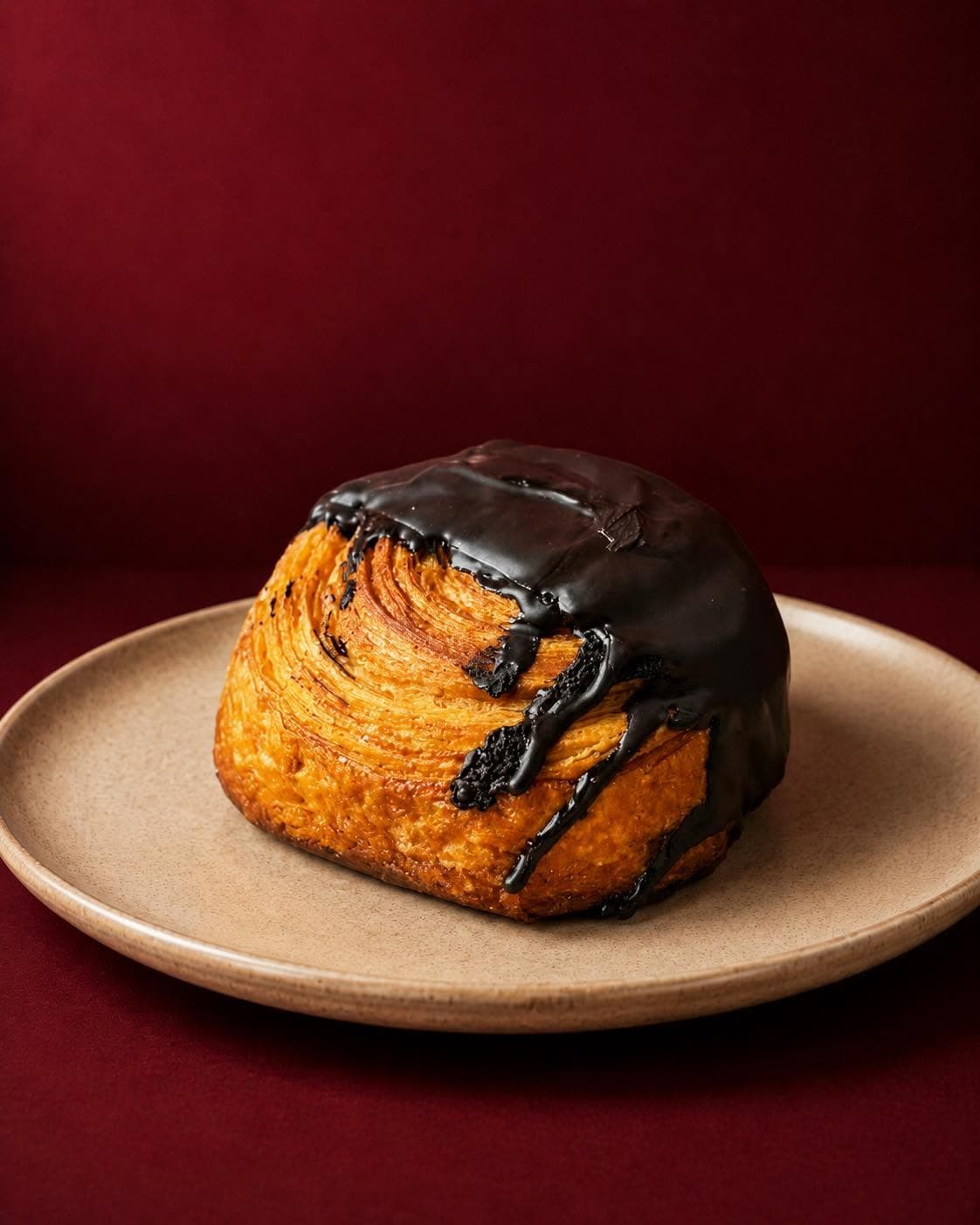 Chocolate Coma kouign amann on a plate, chocolate running down its layers
